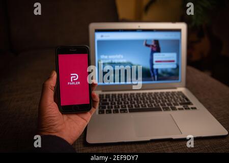 Parler app on the iPhone display standing in front of a macbook.  Parler is a new social networking service very popular during the US elections Stock Photo