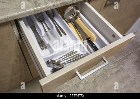 set of knives, forks and  spoons on the shelf in the kitchen cabinet Stock Photo