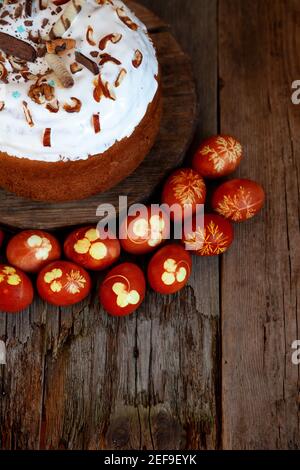 Easter cake and colored eggs. Rustic food on a wooden table. Egg colored with onion peel. Clover and dill leaves pattern. Classic food for the Easter Stock Photo