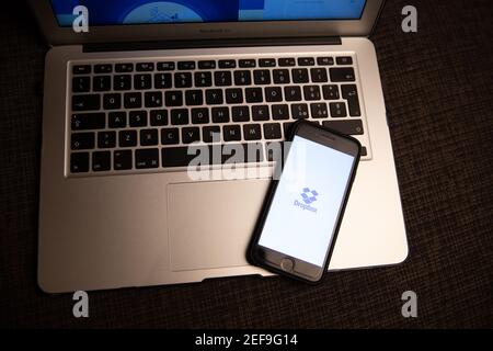 Dropbox logo on a smartphone screen resting on a laptop. Dropbox is a file hosting service that offers cloud storage and cloud services Stock Photo
