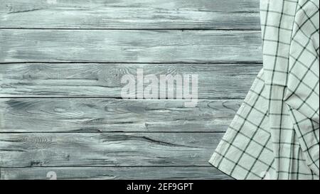 Gray wooden table with linen kitchen towel or textile napkin flat lay. Blue tablecloth on old gray wood tabletop. Copy space for text. Can use as mock up for design. Stock Photo