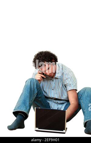 Young man talking on a mobile phone and using a laptop Stock Photo