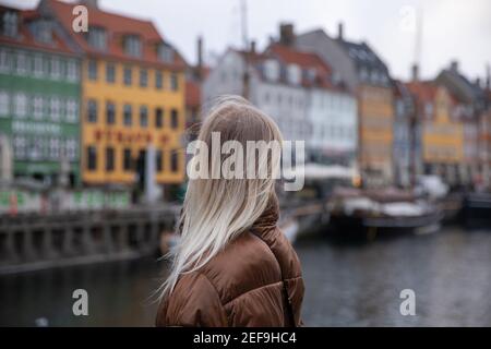 Close-up of a girl's head from behind looking at the colorful houses at Nyhavn in Copenhagen, Denmark Stock Photo