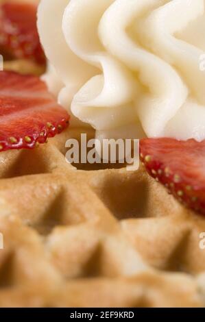 Close-up of a waffle with whipped cream and strawberry slice on it Stock Photo