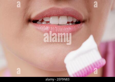 Close-up of a young woman with a toothbrush in front of her mouth Stock Photo