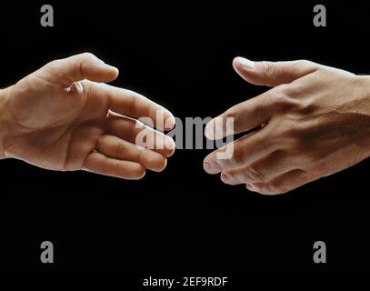 Close-up of two hands reaching towards each other Stock Photo