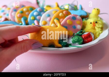 Girl's hand takes yellow cookies in the shape of a rabbit decorated for the Easter holiday from a plate Stock Photo