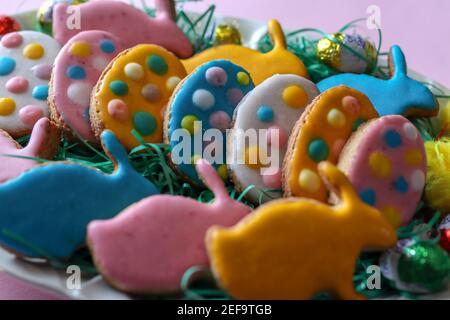 Homemade cookies in the shape of colorful eggs on a plate decorated for the Easter holiday Stock Photo