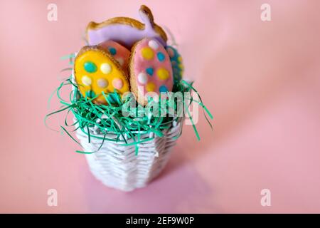 Homemade cookies in the shape of eggs and rabbit in a retro basket on pink background. Easter holiday concept food decoration Stock Photo