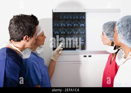 Side profile of a male surgeon and three female surgeons looking at a MRI scan Stock Photo