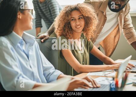 Three multiracial young people having a work-related conversation Stock Photo