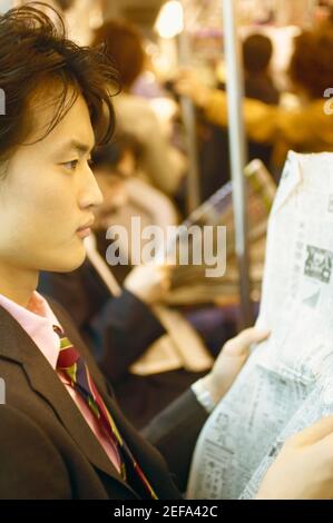 Side profile of a businessman reading a newspaper in the train Stock Photo