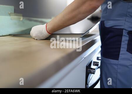 Gloved craftsman installs hob in kitchen closeup Stock Photo