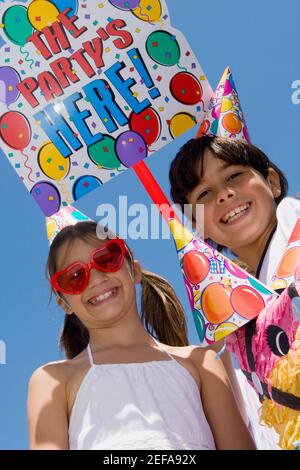 Portrait of a girl with her brother wearing birthday hats and smiling