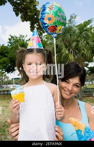 Portrait of a girl holding a balloon and smiling with her mother Stock Photo