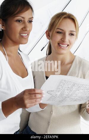 Two female architects holding a blueprint and smiling Stock Photo