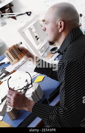 Side profile of an architect holding an architectural model of a building and looking away Stock Photo