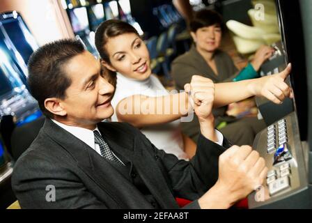 Side profile of a mature man playing on a slot machine with a teenage girl beside him Stock Photo