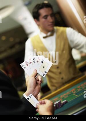 Young man holding playing cards and hiding an ace in his cuff Stock Photo