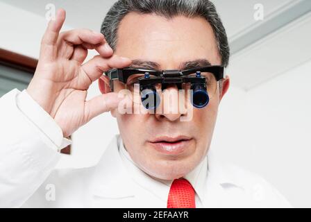 Close-up of a male doctor adjusting lupa binoculars Stock Photo
