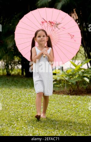 Girl walking in a park with an umbrella Stock Photo