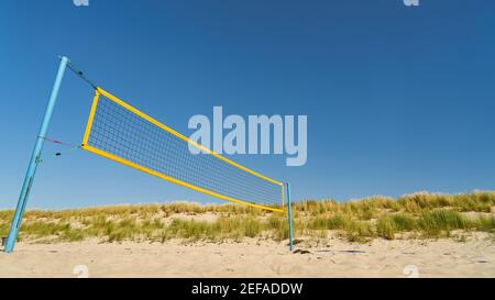 Volleyball net on the sandy beach of the Baltic Sea against a blue sky Stock Photo