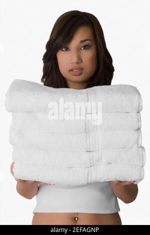 Portrait of a young woman holding a stack of folded towels Stock Photo