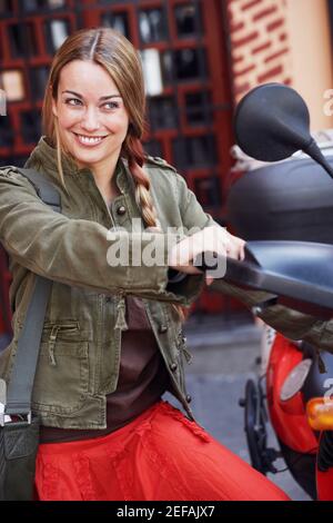 Close-up of a young woman looking at the rear-view mirror of a scooter Stock Photo