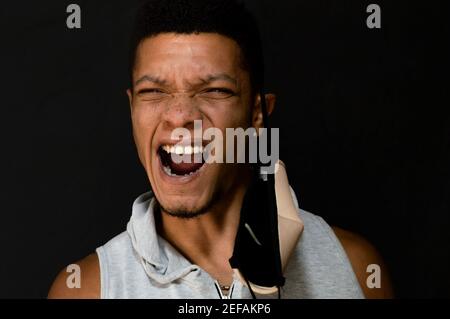 Young latino man giving a cry of liberation by removing his face mask Stock Photo