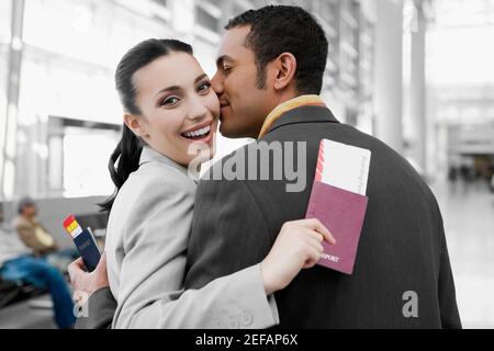 Close up of a businessman kissing a businesswoman at an airport Stock Photo