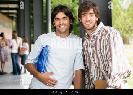 Portrait of two male university students standing in a corridor and smiling Stock Photo