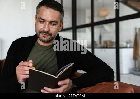 Confident young business man taking notes while sitting in the modern office Stock Photo