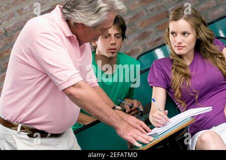 Professor assisting his students in a classroom Stock Photo