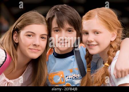 Portrait of a schoolboy with two schoolgirls smiling together Stock Photo
