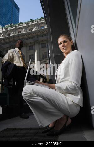 Portrait of a businesswoman opening a briefcase with two businessmen standing in the background Stock Photo