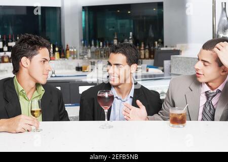 Three businessmen sitting at a bar counter Stock Photo