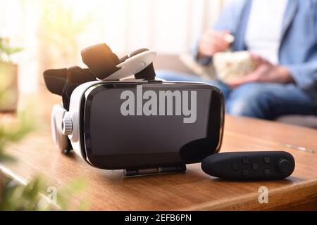 White and black virtual reality headset and joystick controller on wooden table in living room Stock Photo