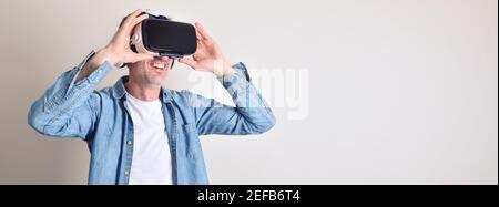 Smiling man dressed casual watching content in virtual reality glasses with clear isolated background Stock Photo