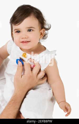 Close up of a personÅ½s hand holding a pacifier in front of a girl Stock Photo