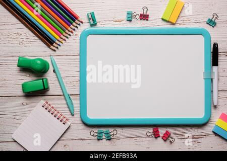 School supplies for homeschool laid out on a white wooden table with a plain white board that can have text and images placed on it Stock Photo