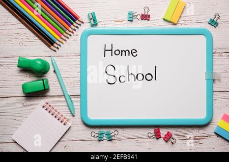School supplies for homeschool laid out on a white wooden table with a white board with the words Home School written on it Stock Photo