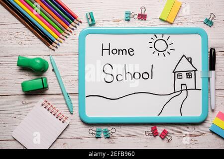 School supplies for homeschool laid out on a white wooden table with a white board with the words Home School written on it Stock Photo