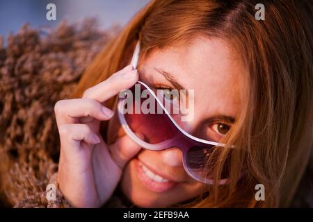 Portrait of a mid adult woman peeking over her sunglasses Stock Photo