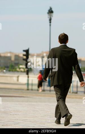 Rear view of a businessman walking on a sidewalk, Bordeaux, Aquitaine, France Stock Photo