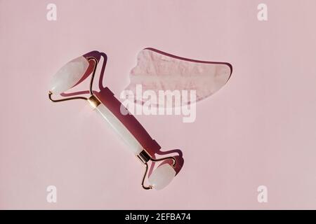 Jade roller and gua sha massage tool on pink background Stock Photo