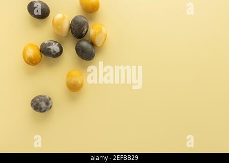 Golden and silver easter eggs scattered on yellow background, festive easter concept Stock Photo
