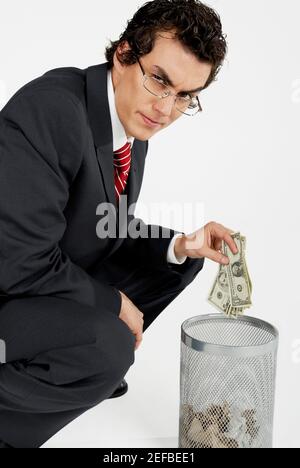 Portrait of a businessman throwing paper currency into a wastepaper basket Stock Photo