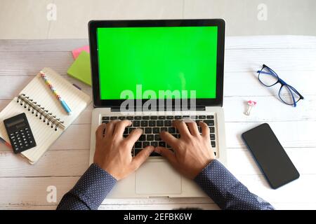 top view of young man using laptop with blank screen on office desk. Stock Photo