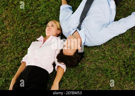 High angle view of a businesswoman and a businessman lying on the grass Stock Photo