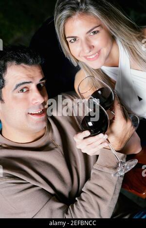 Portrait of a mid adult man and a mid adult woman holding glasses of red wine and smiling Stock Photo